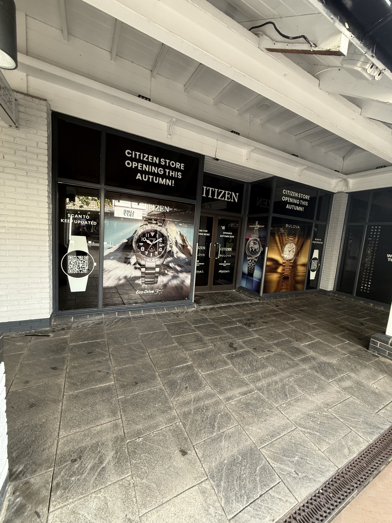 Citizen & Bulova window graphics. Watch-brand campaign graphics and opening messages across a retail shopfront.